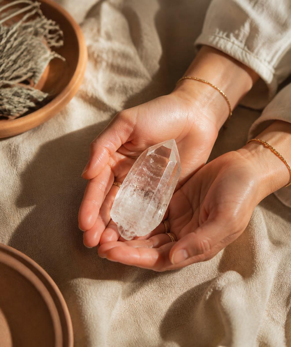 Mãos femininas segurando um cristal sobre tecido natural